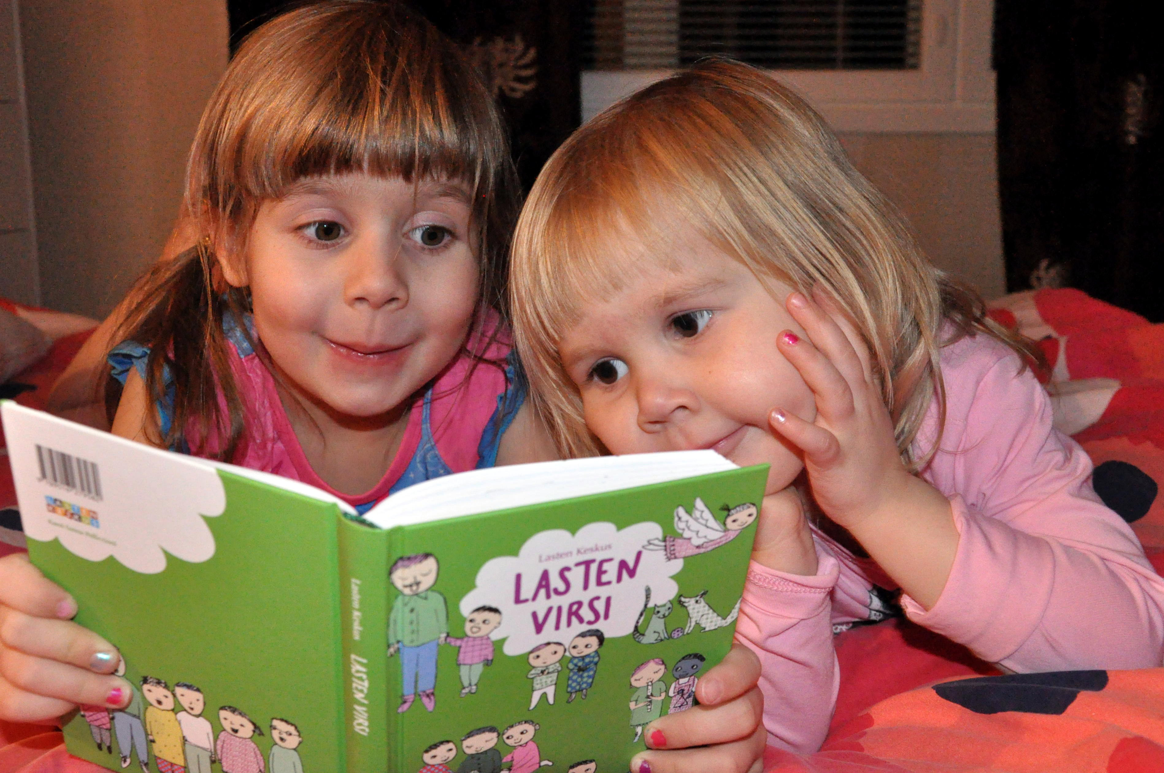 kaksi tyttöä lukee lasten virsikirjaa
